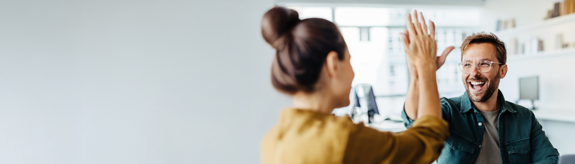 Mann und Frau in einem Büro geben sich ein High-Five.