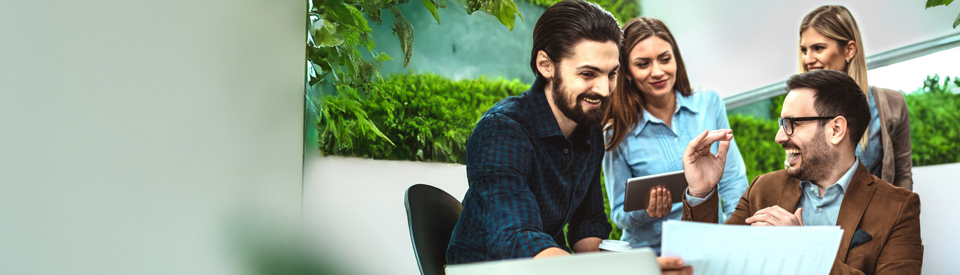 Eine Gruppe von Mitarbeitenden sitzt gemeinsam an einem Tisch und diskutiert ein Projekt